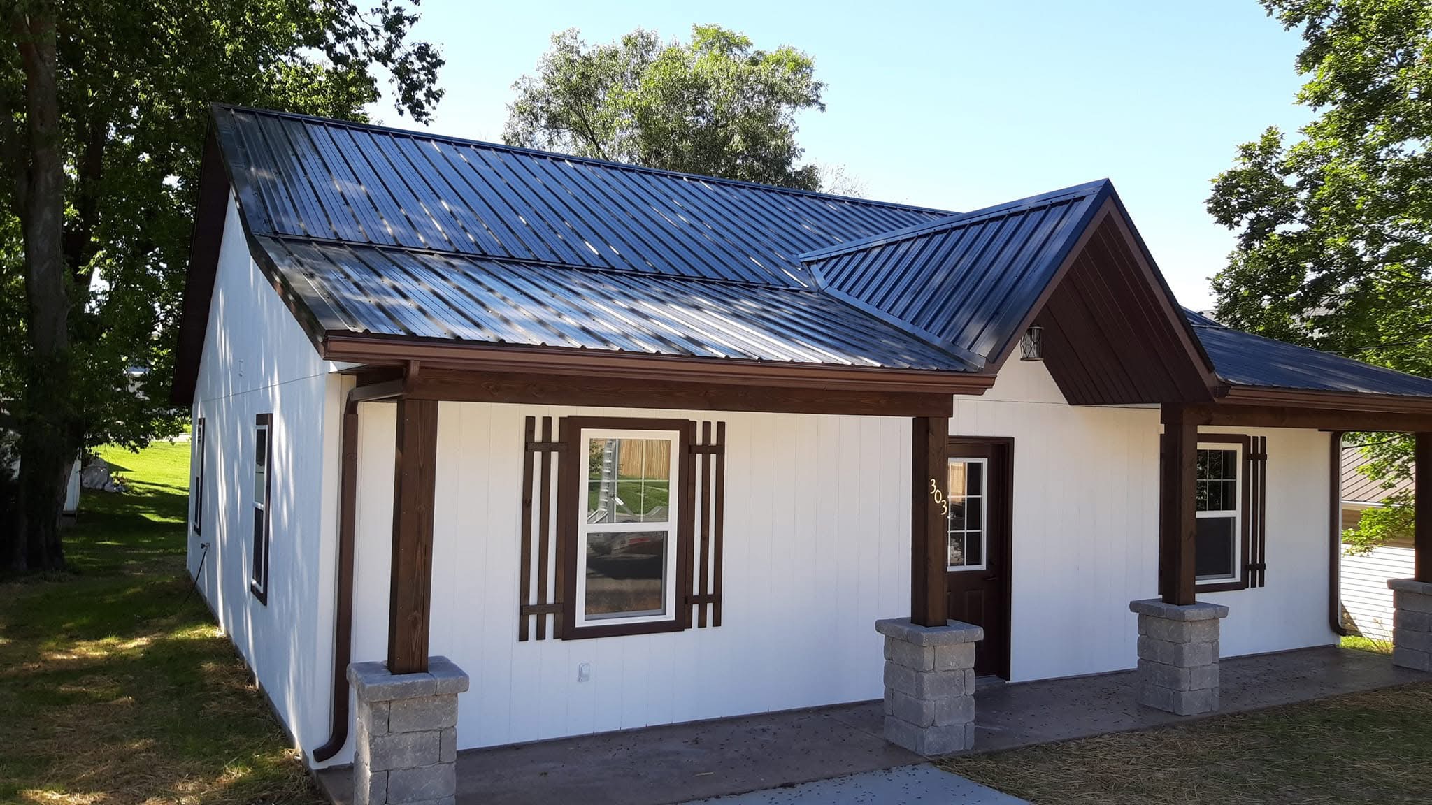 Dark Metal Roof Installation on a Charming White Cottage
